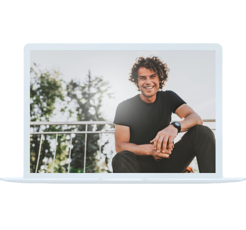 Man sitting outdoors on a laptop screen, smiling and relaxed, connected with online alcohol addiction treatment.