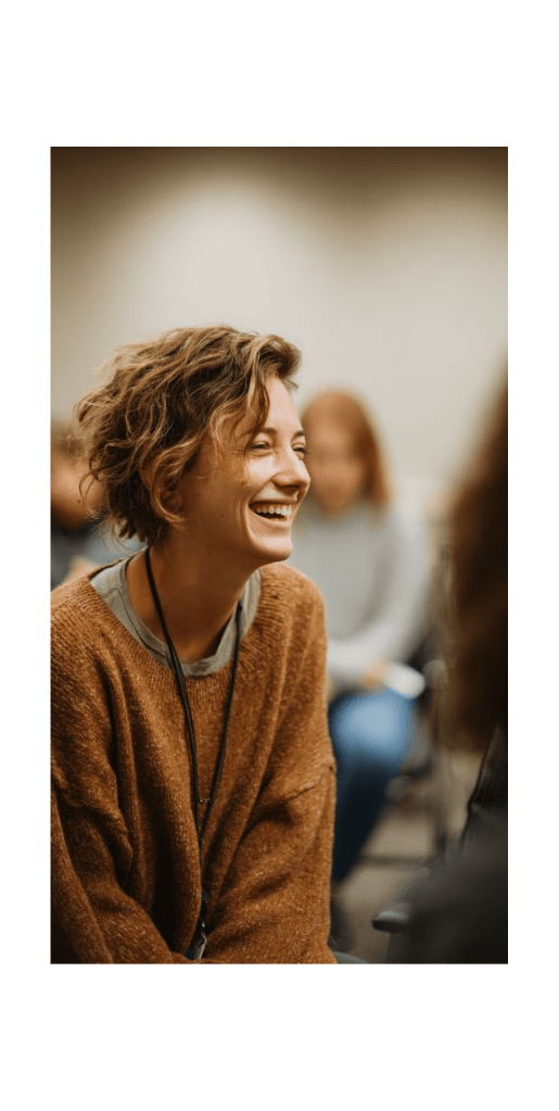 Woman laughing in a group setting, highlighting support found in online alcohol addiction treatment.
