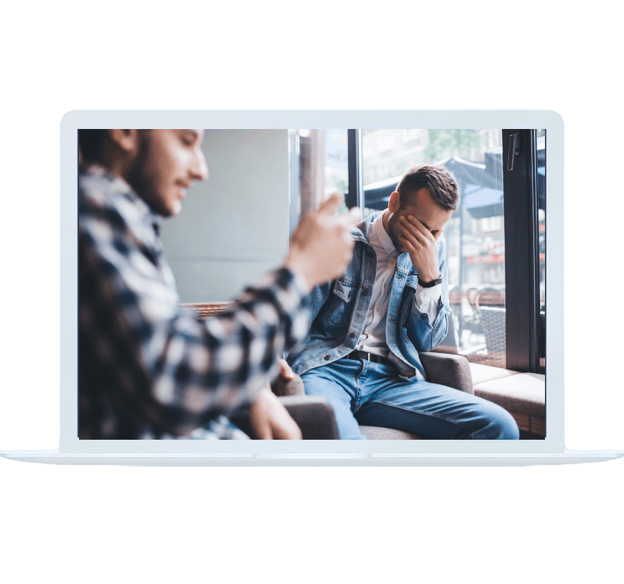 Man covering his face during a conversation in a café, symbolizing stress addressed with online anxiety counseling