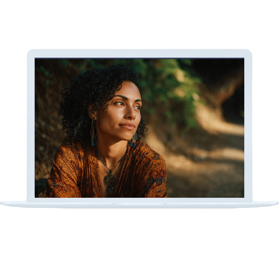 A thoughtful woman sitting outdoors with soft light on her face, representing healing through online trauma counseling.