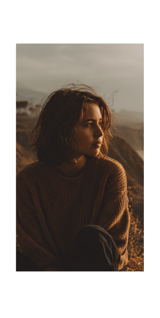 A young woman in a sweater gazing thoughtfully outdoors, symbolizing reflection and healing with online bipolar counseling.